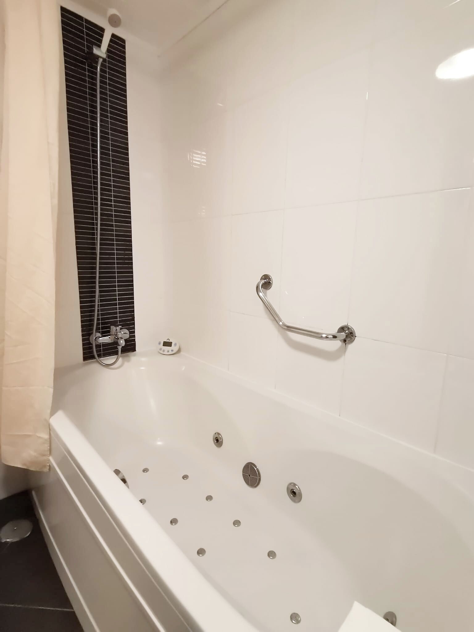 Une salle de bain moderne dotée d’une grande baignoire, d’un pommeau de douche à main et d’une barre de douche à main.