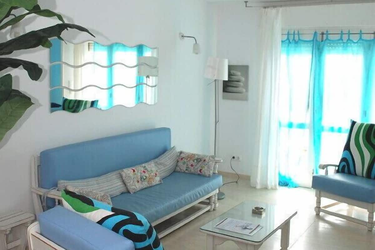 A living room with a blue sofa, a matching armchair, a coffee table, and a large mirror.
