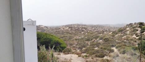 Un balcón con vistas a un paisaje desértico, que incluye vegetación escasa y colinas.
