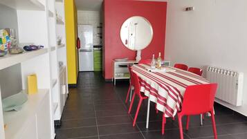A modern dining area with a red and white striped tablecloth, red chairs, and a large round mirror on the wall.