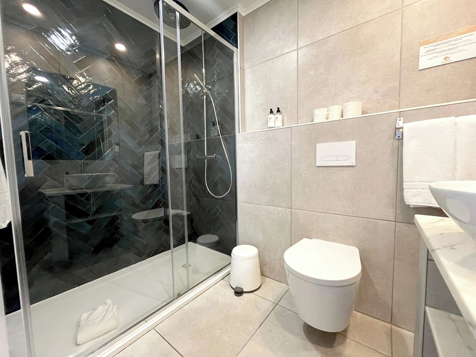 Ein modernes Badezimmer mit einer gläsernen Duschkabine, Toilette und Waschbecken.