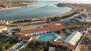 Oversigtsbillede af et kystresort med swimmingpool, adgang til stranden og en lysthavn.