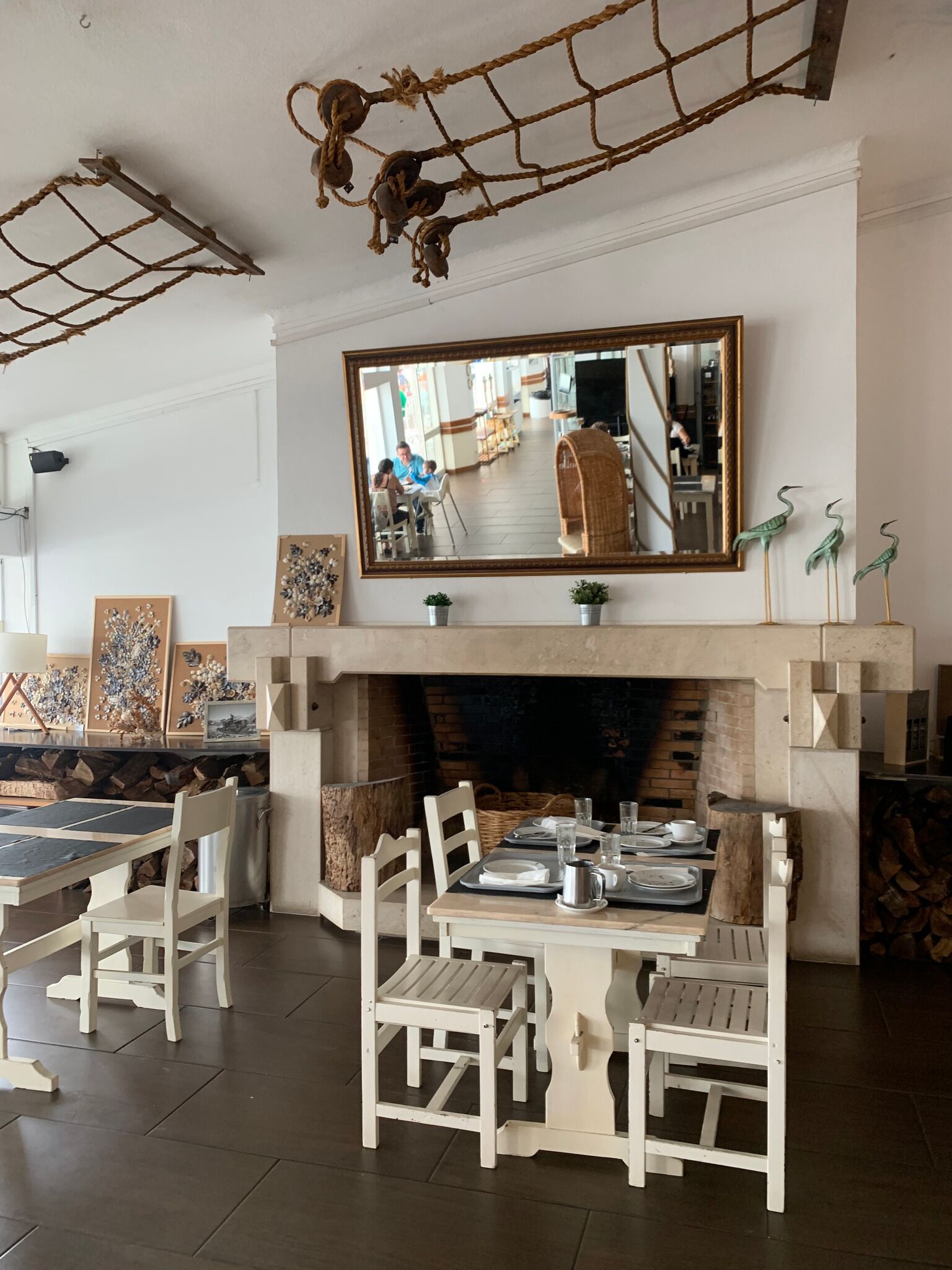 Un coin repas avec une cheminée, des chaises blanches et une table dressée pour quatre personnes.