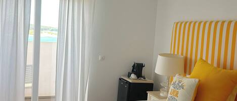 Une chambre d’hôtel avec un lit, une table de chevet, une lampe et une vue sur la plage.