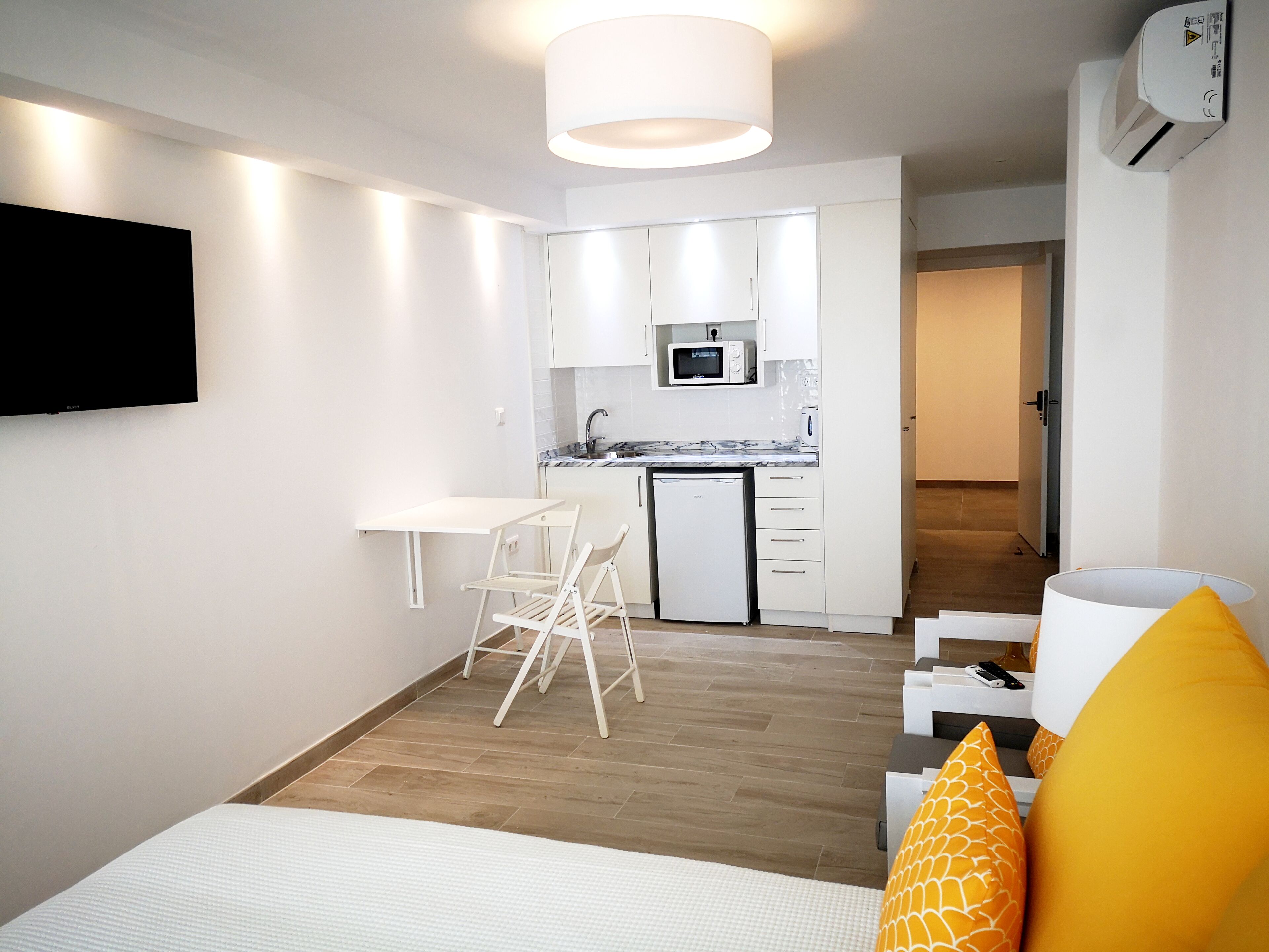 A compact living space with a kitchenette, a dining area, and a bed.