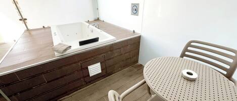 Un espacio de spa con una bañera de hidromasaje, una mesa y una silla.