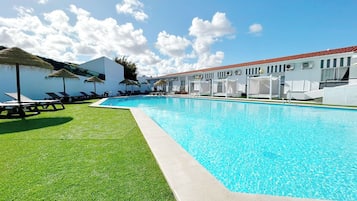 Alberca techada, alberca al aire libre y sombrillas en la alberca