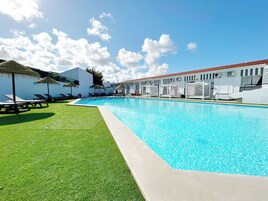 Una piscina techada, una piscina al aire libre, sombrillas