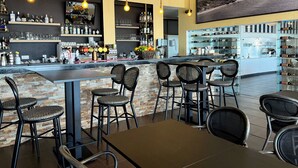 En bar med en bordplade i sten, sorte fletstole og et vinskab i baggrunden.