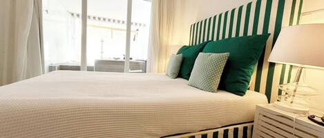 Un dormitorio con una cama grande, cabecera a rayas y una mesita de noche con lámpara.