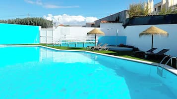Alberca techada, alberca al aire libre y sombrillas en la alberca