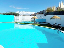 Una piscina techada, una piscina al aire libre, sombrillas