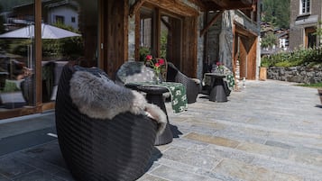 A cozy outdoor seating area with wicker furniture and a stone floor.