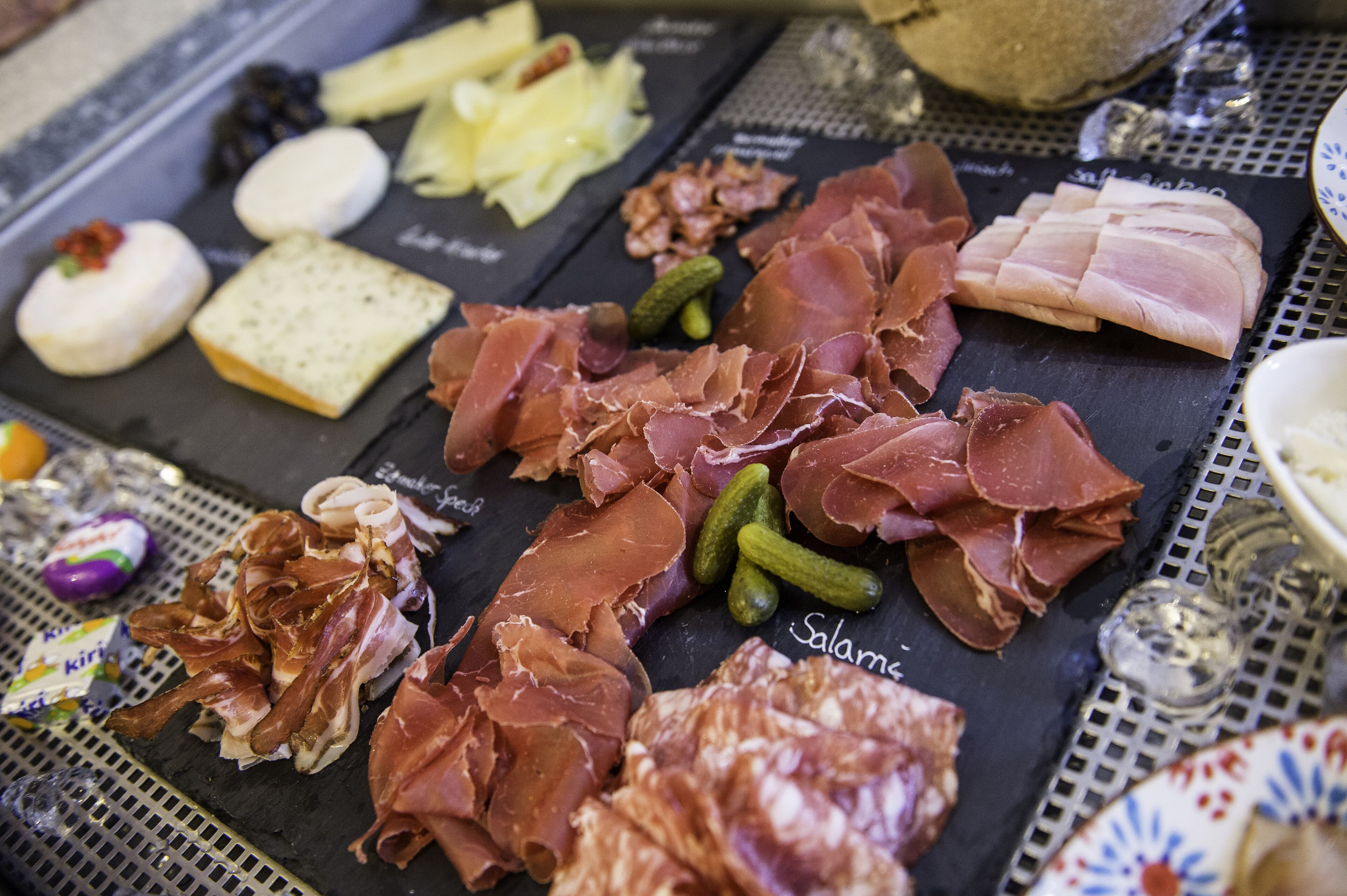 A charcuterie board with various meats, cheeses, and pickles.