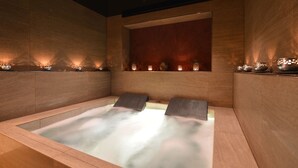 A spa room with a large bathtub, wooden walls, and decorative lights.