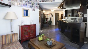A living room with a sofa, a coffee table with plants, a red cabinet, and a wall decorated with framed photos. - Hotel Astoria am Urachplatz (Stuttgart)