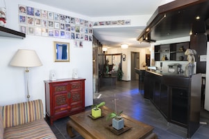 Una sala de estar con un sofá, una mesa de centro con plantas, un armario rojo y una pared decorada con fotos enmarcadas.