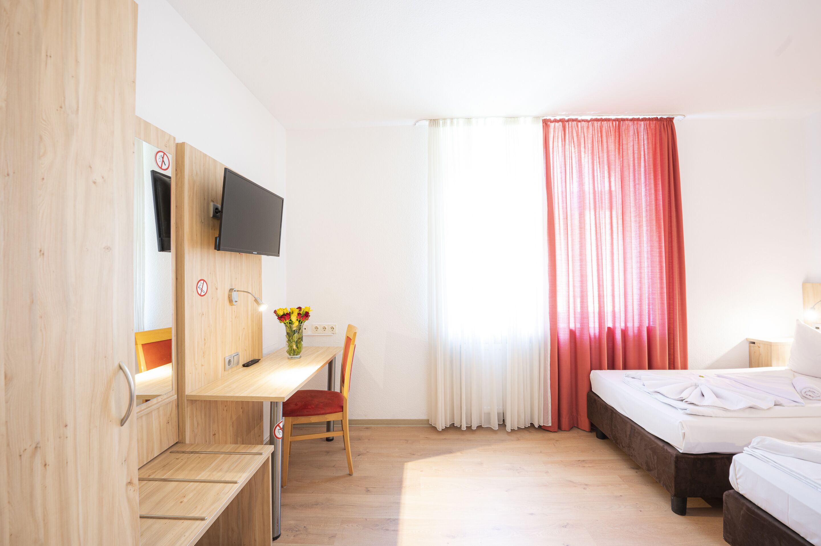 A hotel room with a wooden desk, chair, and a bed.