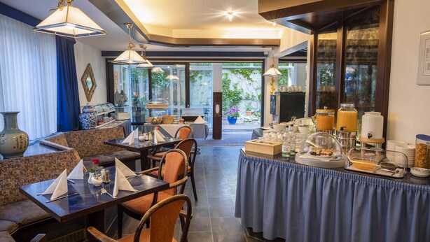 A dining area with tables and chairs, a buffet with food and beverages, and a view of the outdoors. - Hotel Astoria am Urachplatz (Stuttgart)