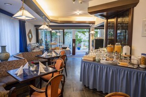 A dining area with tables and chairs, a buffet with food and beverages, and a view of the outdoors. - Hotel Astoria am Urachplatz (Stuttgart)