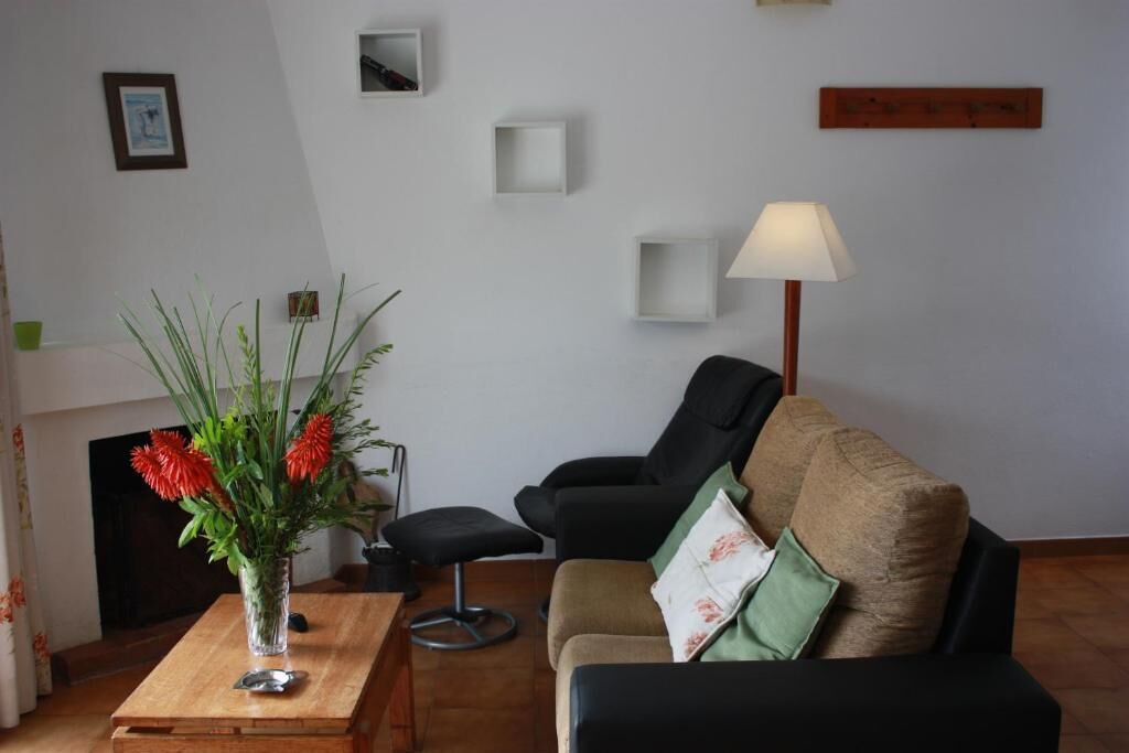 A living room with a sofa, a coffee table, a vase with flowers, a lamp, and a fireplace.