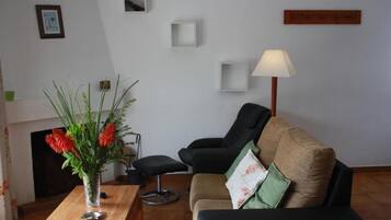 A living room with a sofa, a coffee table, a vase with flowers, a lamp, and a fireplace.