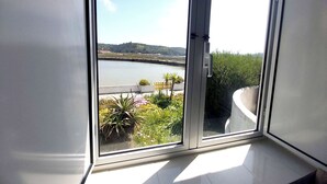 A room with a large sliding glass door leading to a balcony with a view of a lake and greenery.