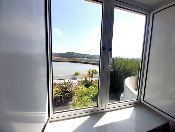 Una stanza con un'ampia porta-finestra scorrevole che dà su un balcone con vista su un lago e sul verde.