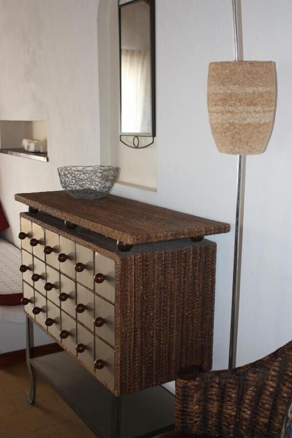 A wooden cabinet with drawers and a bowl on top, a mirror on the wall, and a floor lamp. - Moinho Da Asneira - Duna Parque Resorts & Hotels (Odemira)