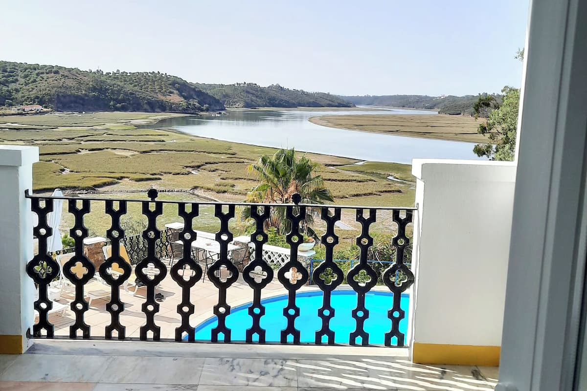 A balcony with a view of a river and distant hills.