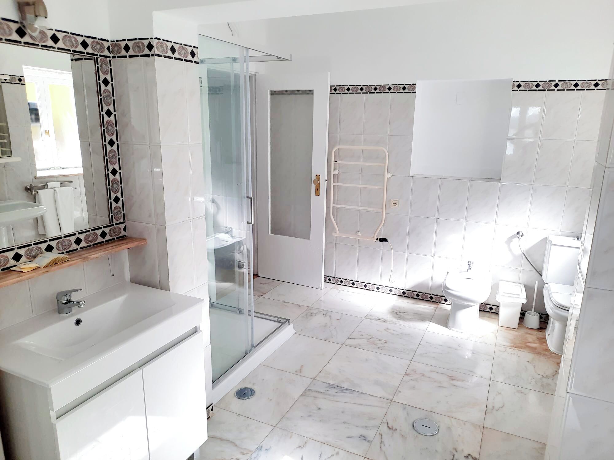 A modern bathroom with a glass shower enclosure, a white sink, and a toilet.