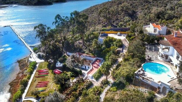 A coastal property with a swimming pool, a dock, and a boat storage area.