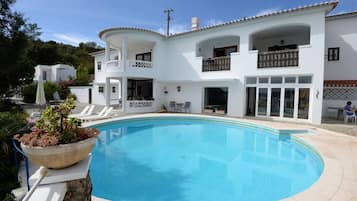 Una piscina al aire libre, sombrillas, sillones reclinables de piscina