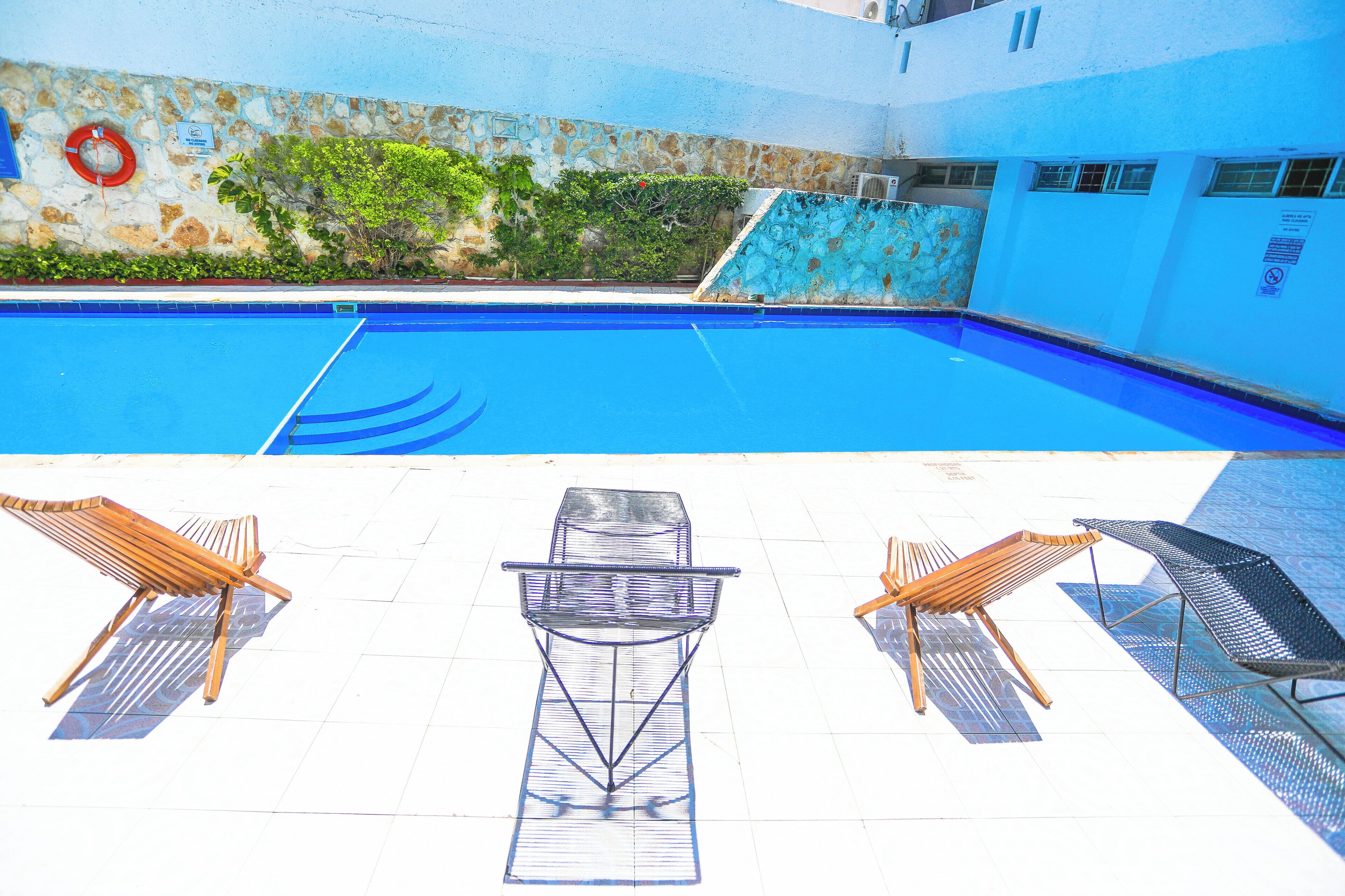 A swimming pool with lounge chairs and a lifebuoy on the wall.