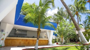 A hotel with a blue and white exterior, a tiled entrance, and palm trees in the garden area. - Caribe Internacional Cancun (Cancun)