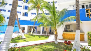 A hotel courtyard with palm trees, a pool, and outdoor seating areas. - Caribe Internacional Cancun (Cancun)