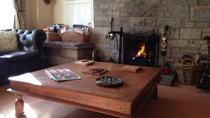 A cozy living room with a stone fireplace, a leather sofa, and a wooden coffee table with magazines and games. - Plumpton Court (York)