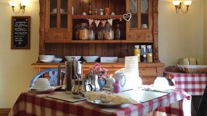 A dining area with a wooden cabinet, jars, and a table set with a red and white checkered tablecloth. - Plumpton Court (York)