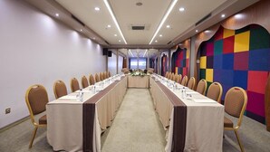 A conference room with a long table, chairs, and a colorful wall. - Olimpiyat (Istanbul)