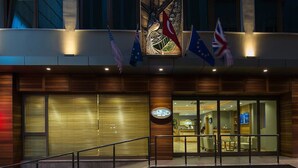 A hotel entrance with flags, a reception desk, and a staircase leading up. - Olimpiyat (Istanbul)