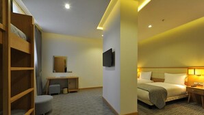 A hotel room with a bunk bed, a desk with a chair, a television, and a bedside table with a lamp. - Olimpiyat (Istanbul)