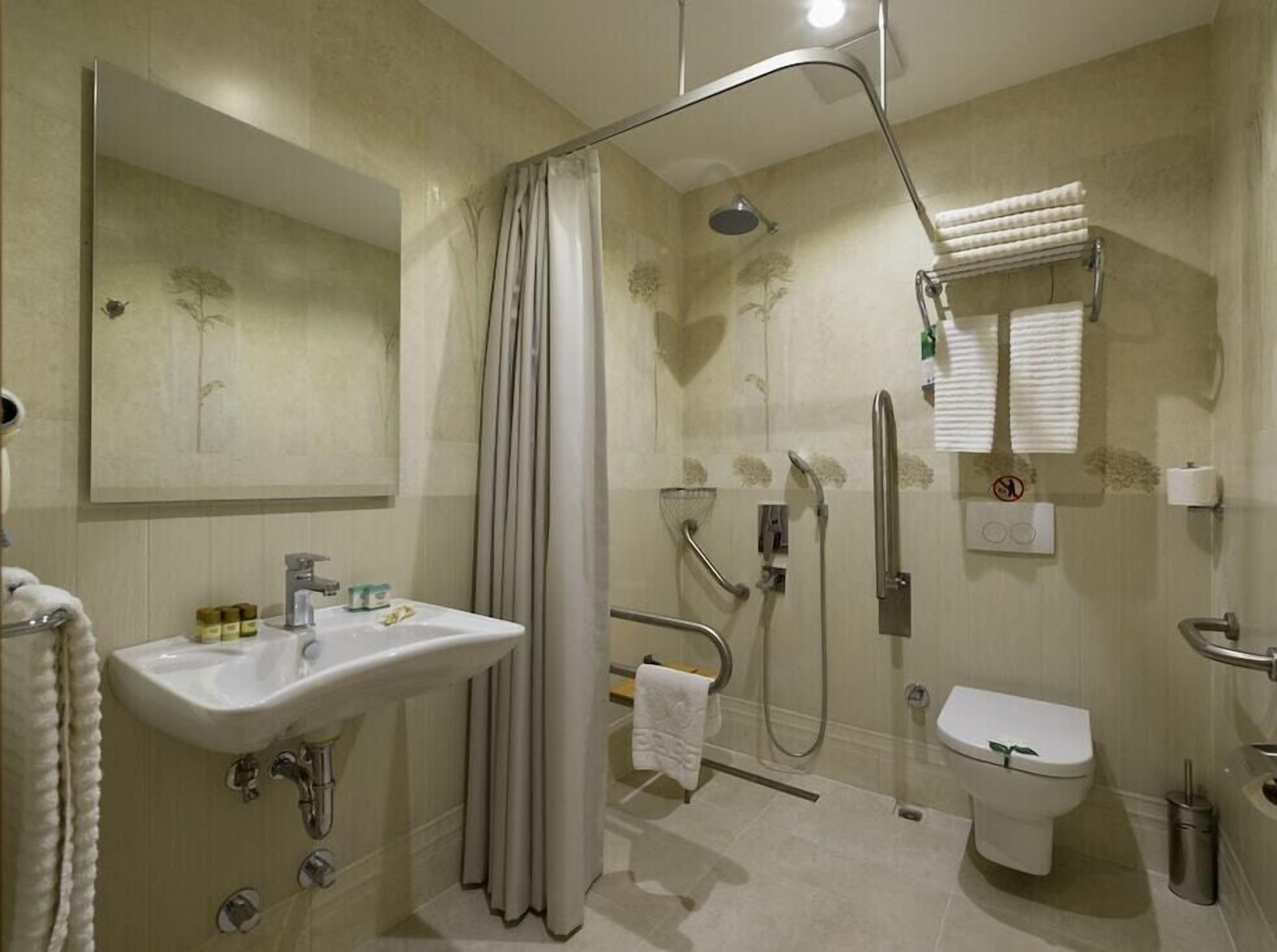 A modern bathroom with a sink, toilet, shower, and a large mirror.