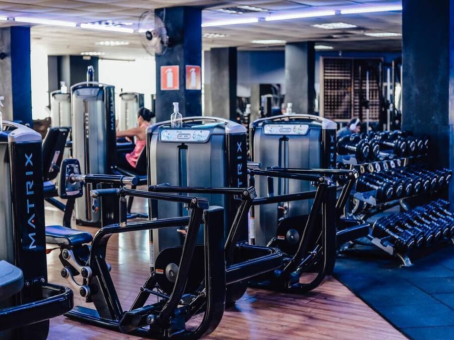 Une salle de sport équipée de divers appareils d’exercice, notamment des tapis de course et des appareils de musculation à poids.
