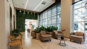 Un vestíbulo moderno con una pared verde, asientos cómodos y ventanas amplias.