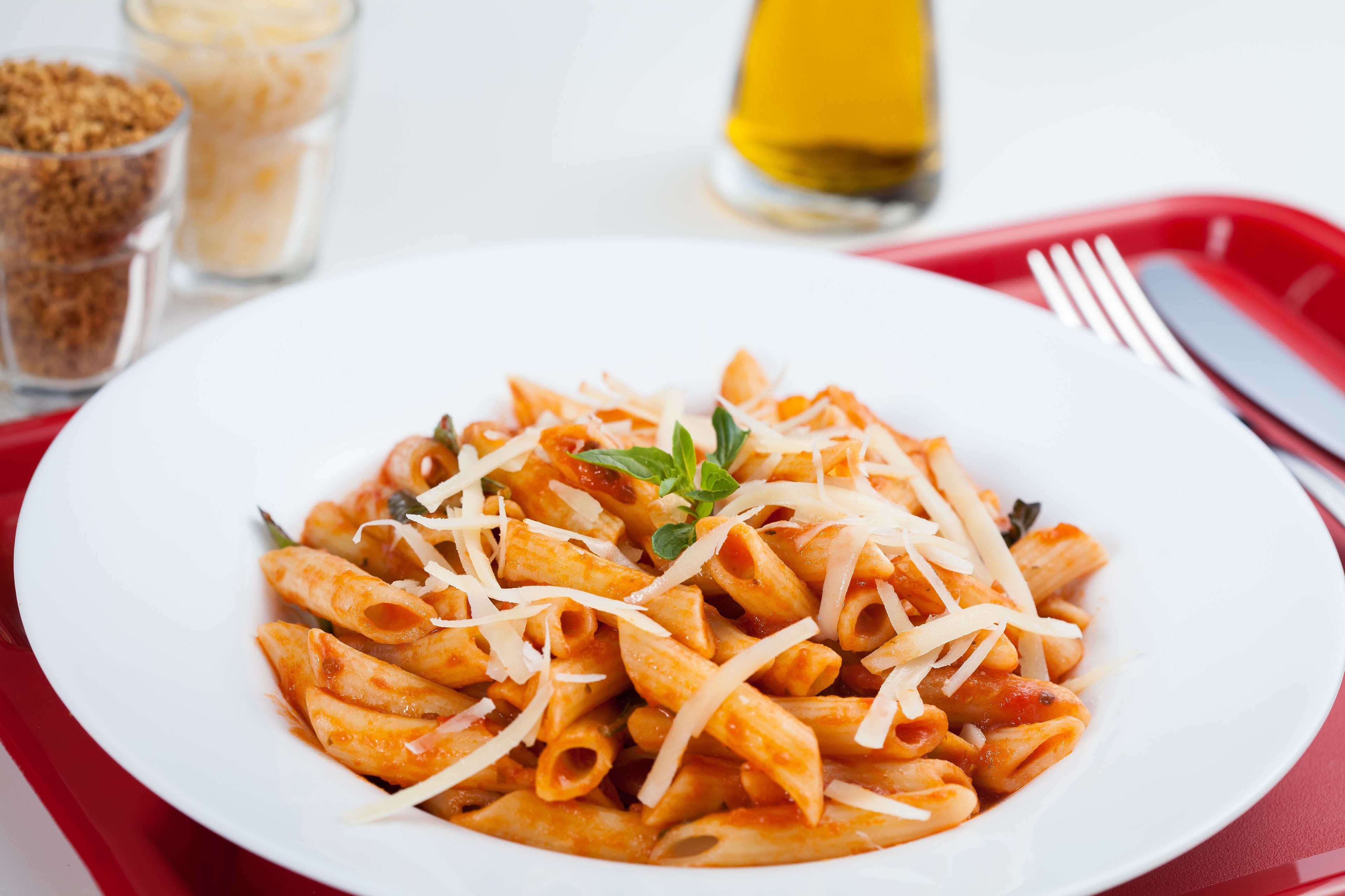Un piatto di pasta con formaggio e un rametto di erba aromatica.