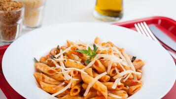 Un piatto di pasta con formaggio e un rametto di erba aromatica.