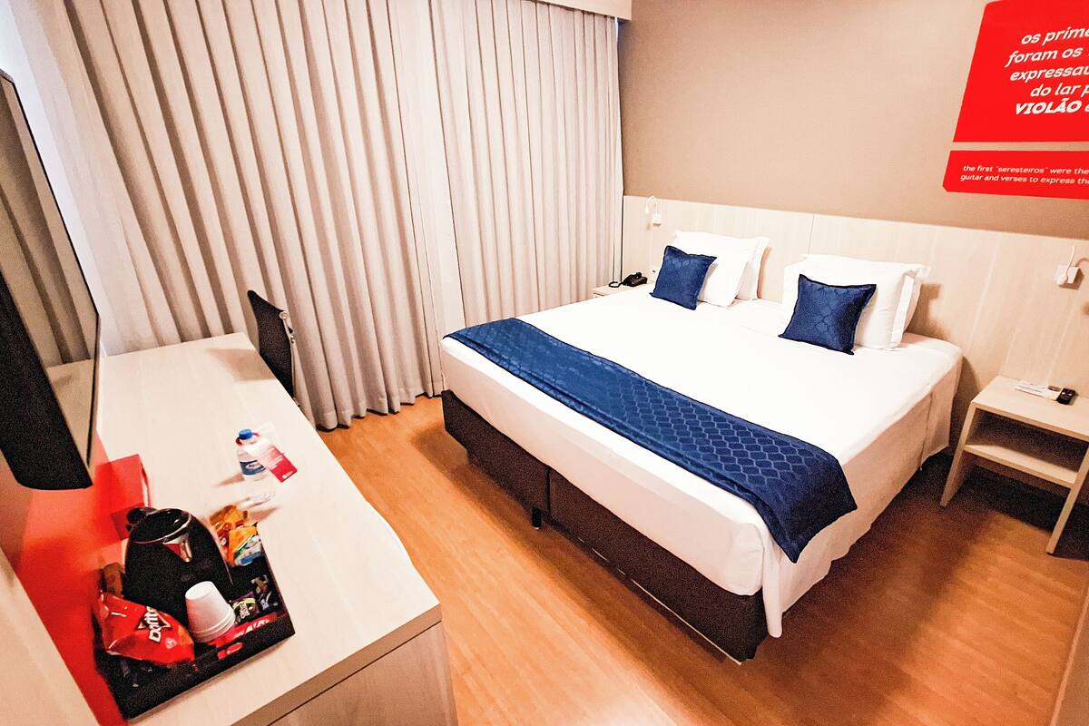 Una habitación de hotel con cama, mesita de noche y escritorio con silla.