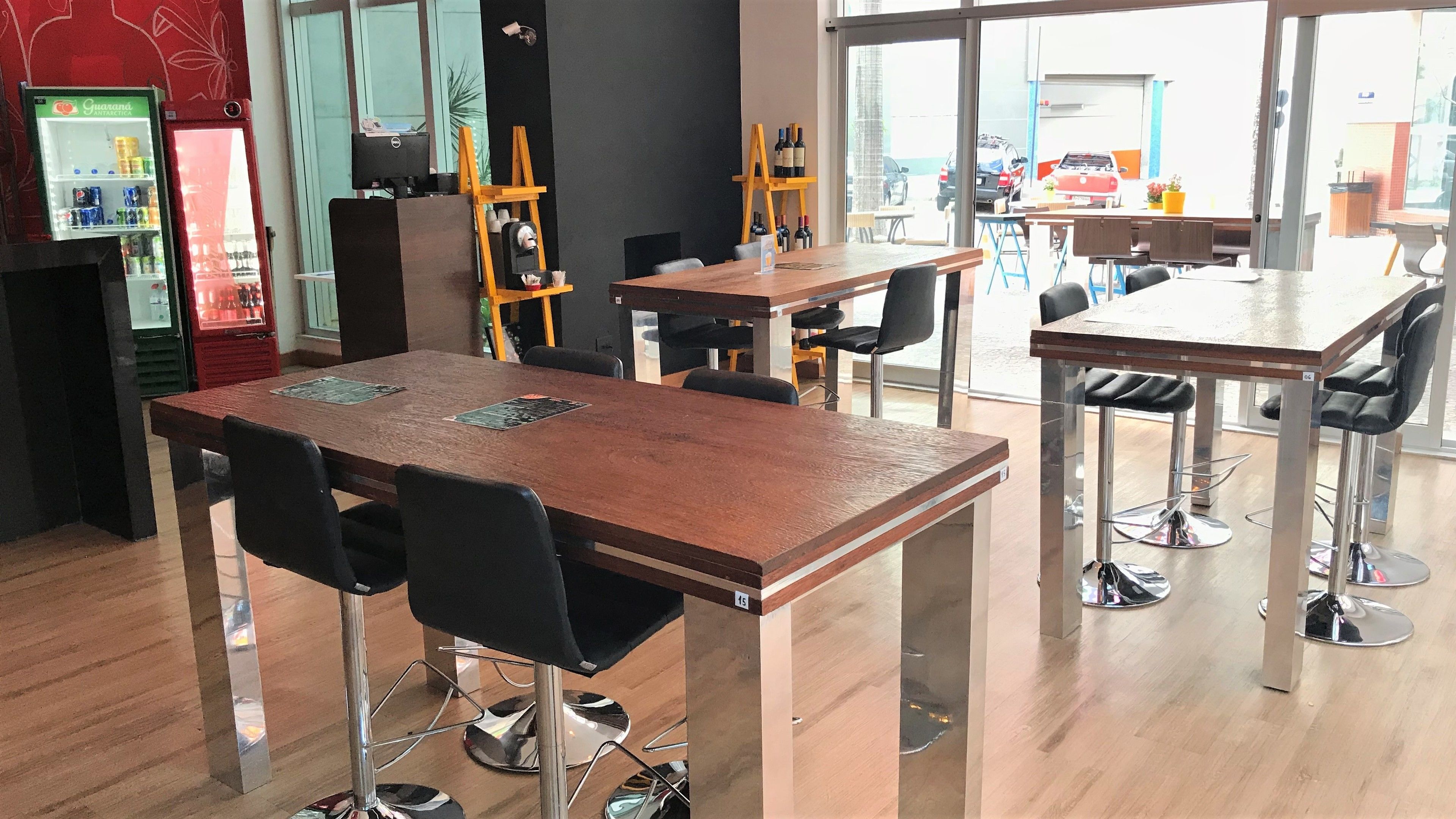 A modern dining area with wooden tables and black chairs, a vending machine, and a wine rack.