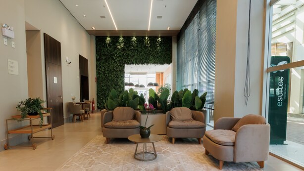 Un lobby moderno con asientos, una pared verde y vistas al exterior.
