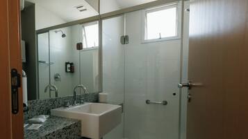 A modern bathroom with a glass shower enclosure, a sink with a granite countertop, and a large mirror.